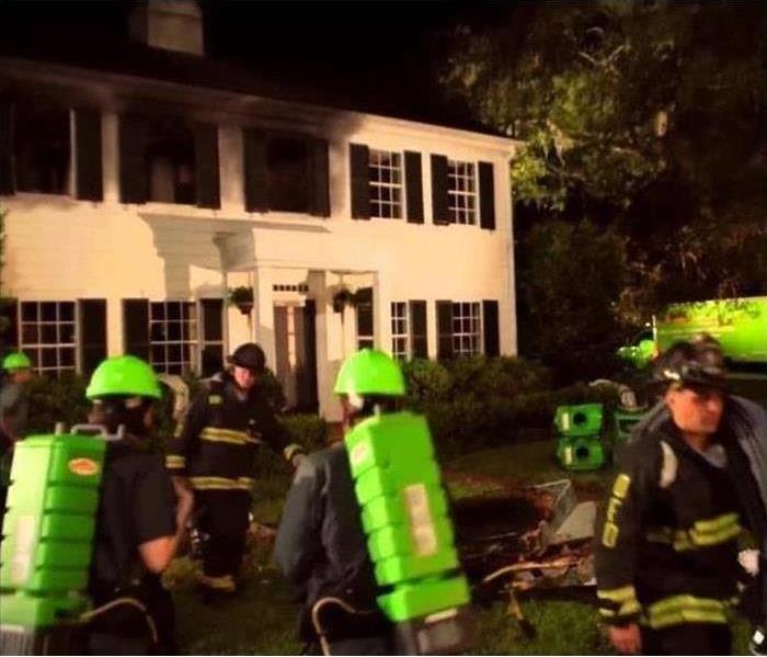 SERVPRO technicians standing in front of a house with smoke damage