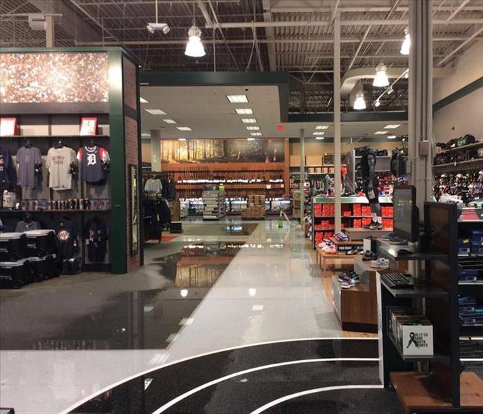 Carpet, tile, and running track flooring covered with water along with clothing racks, display stands, and mannequins